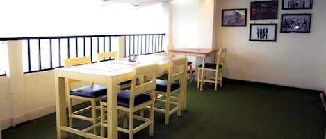 A room with a wooden table and chairs, a small table with a laptop, and framed pictures on the wall.