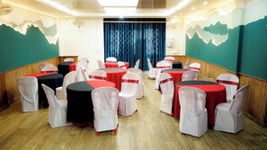 A conference room with round tables, chairs, and a blue curtain backdrop. - The Mystic Hill Hotel-Aizawl Mizoram (Aizawl)