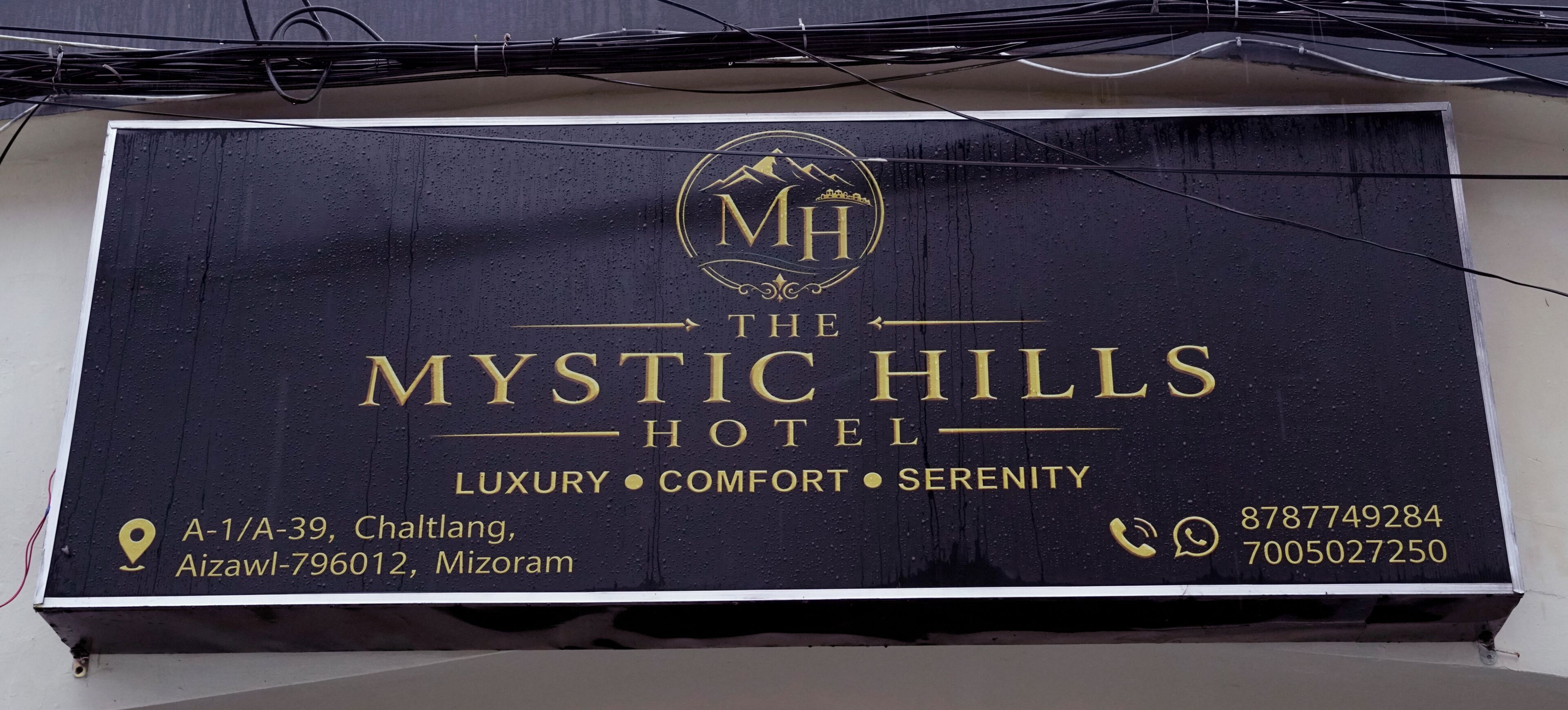 A signboard for The Mystic Hills Hotel with its address and contact numbers.