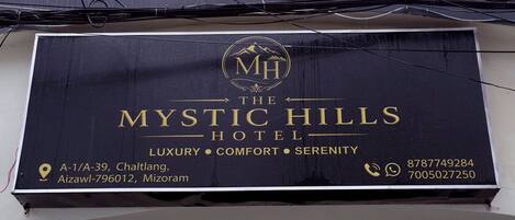 A signboard for The Mystic Hills Hotel with its address and contact numbers.