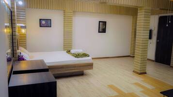 A hotel room with a bed, a bedside table, a mirror, and a wall-mounted picture.