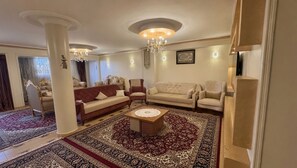 A spacious living room with a large, ornate rug, multiple seating options including sofas and armchairs, and a central coffee table. - Stylish Apt by the Nile, Downtown & Mamsha ahlmasr (Giza Governorate)