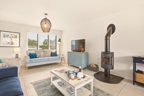 Open-plan lounge with freestanding wood burner and plantation shutter window - Duneside House - North East Escapes (Beadnell)