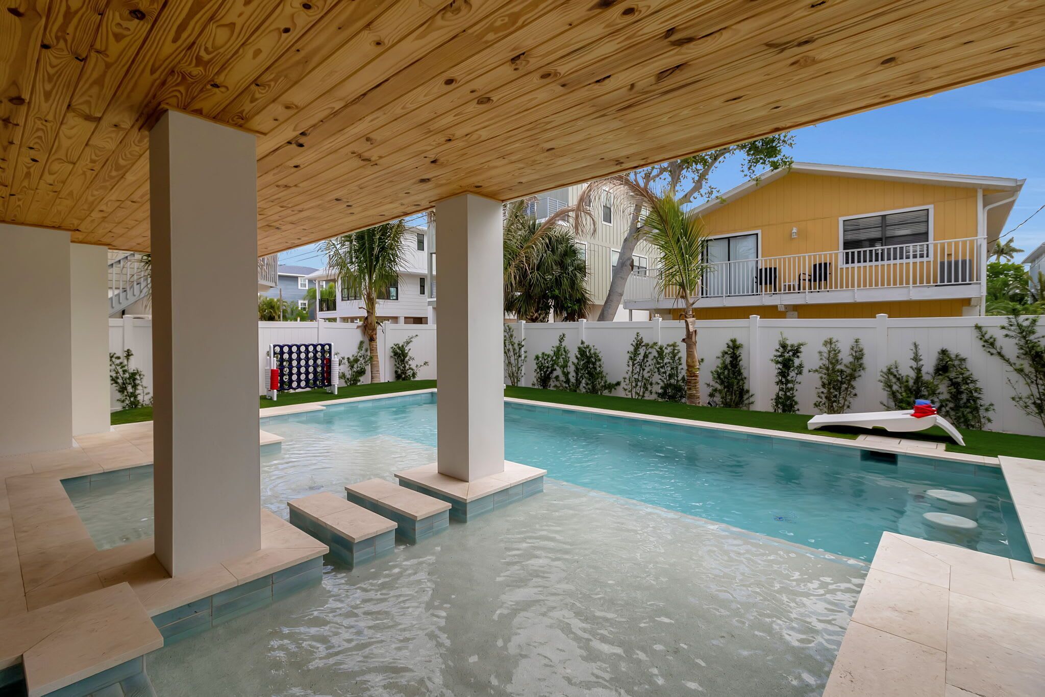 A swimming pool with steps leading into it, surrounded by a wooden pergola.