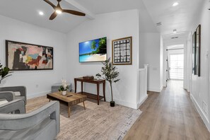 Ein modernes Wohnzimmer mit einer Couch, einem Couchtisch, einem Fernseher, Kunstwerken und einer Pflanze.