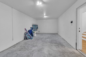 A spacious, empty room with white walls, a concrete floor, and a door leading to a wooden staircase. - Brand New, Heated Pool/Spa, Minutes to Beach (Bradenton Beach)