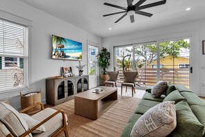 A modern living room with a sofa, chairs, a coffee table, a TV, and a large window with blinds. - Brand New, Heated Pool/Spa, Minutes to Beach (Bradenton Beach)