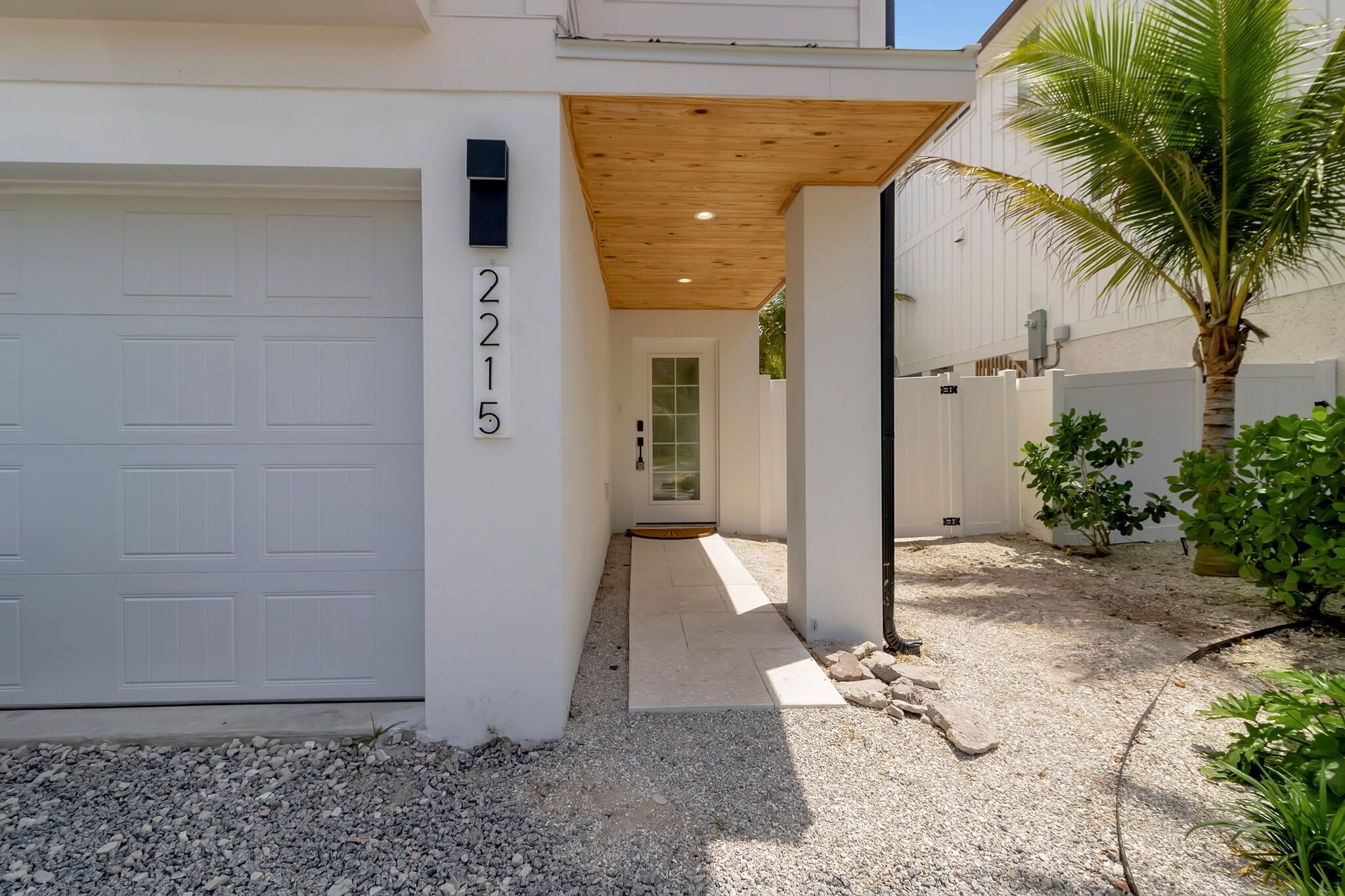 A modern house with a garage, a wooden ceiling, and a gravel driveway.
