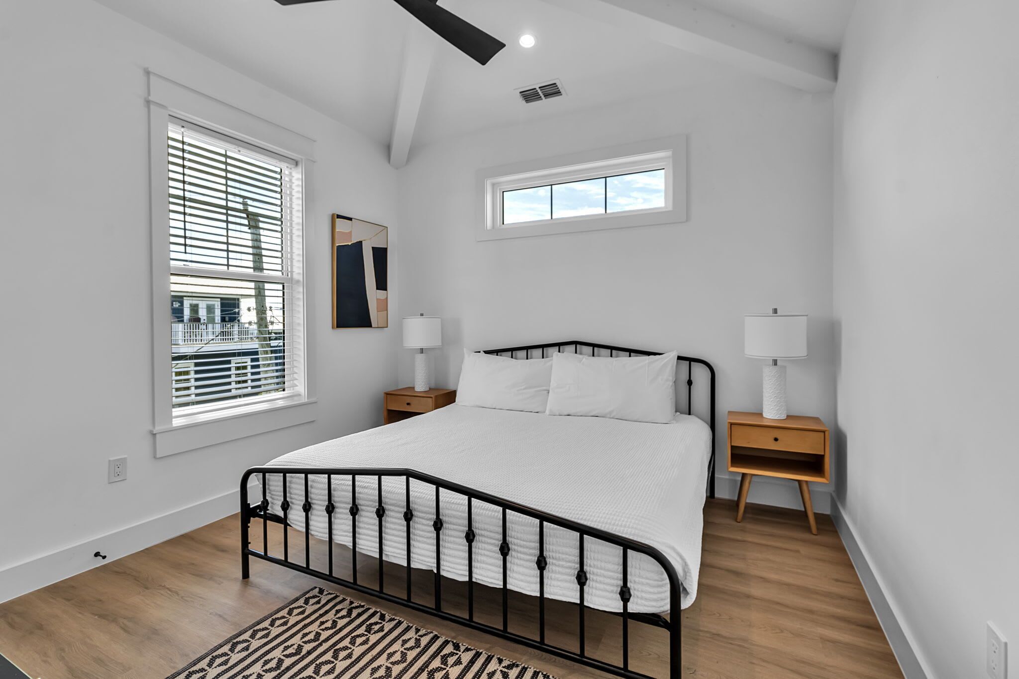 A bedroom with a bed, two bedside tables, a window, and a ceiling fan.
