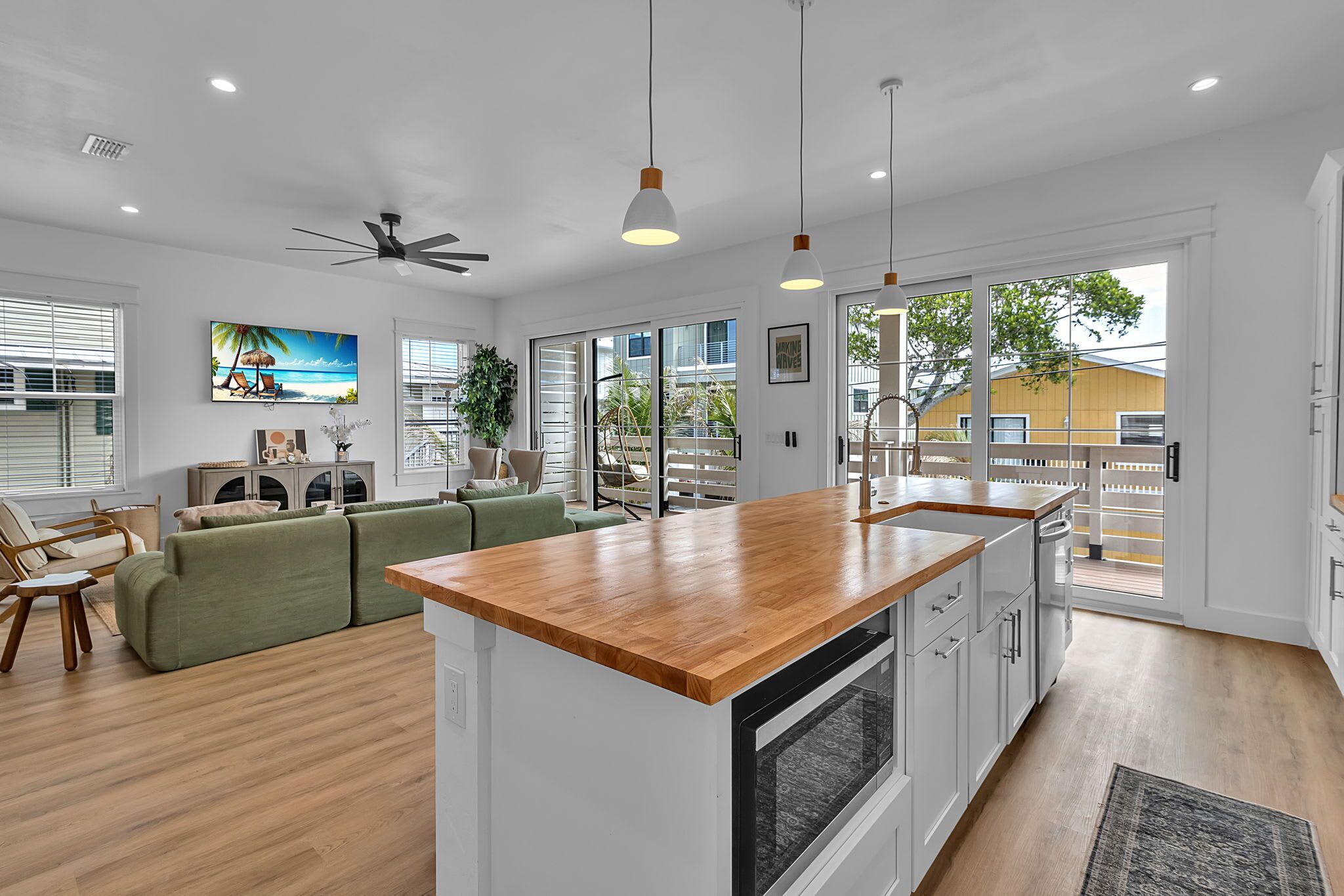 Een moderne keuken met een houten aanrechtblad, een inbouwoven en een grote schuifpui die leidt naar een balkon.