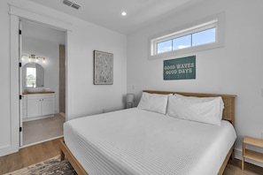 A bedroom with a bed, a window, a door, a mirror, and a wall sign. - Brand New, Heated Pool/Spa, Minutes to Beach (Bradenton Beach)