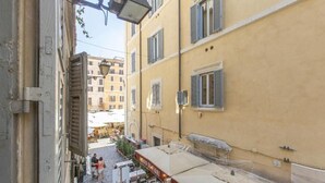 A narrow street with outdoor seating and a building with shutters. - FarneseHouse (Roma)