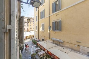 A narrow street with outdoor seating and a building with shutters. - FarneseHouse (Roma)