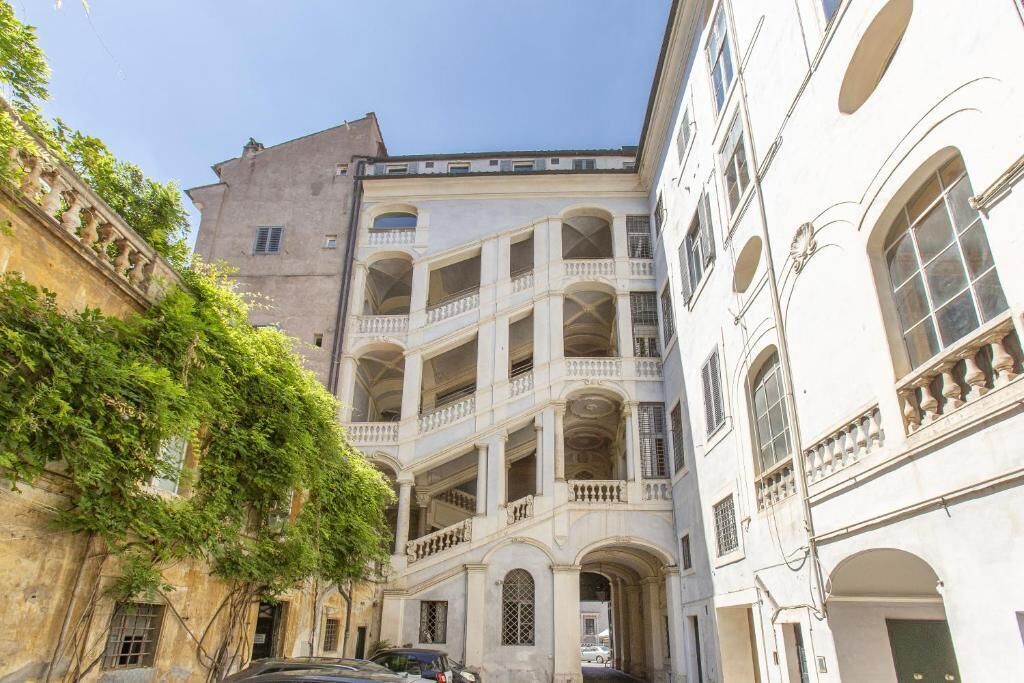 A narrow street with buildings featuring balconies and arched windows.