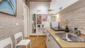A compact kitchen with a wooden countertop, a stainless steel sink, and a white chair. - FarneseHouse (Roma)