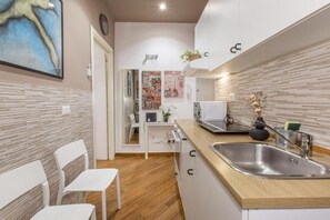 A compact kitchen with a wooden countertop, a stainless steel sink, and a white chair. - FarneseHouse (Roma)