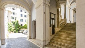 A corridor with a cobblestone floor leading to a staircase with stone balustrades. - FarneseHouse (Roma)
