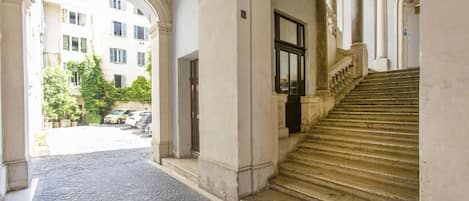A corridor with a cobblestone floor leading to a staircase with stone balustrades.