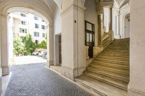 A corridor with a cobblestone floor leading to a staircase with stone balustrades. - FarneseHouse (Roma)