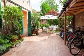 A courtyard with a table and chairs, potted plants, and bicycles. - Apartment for two people in the city center with a garden, bicycles, and a garage (Ferrara)