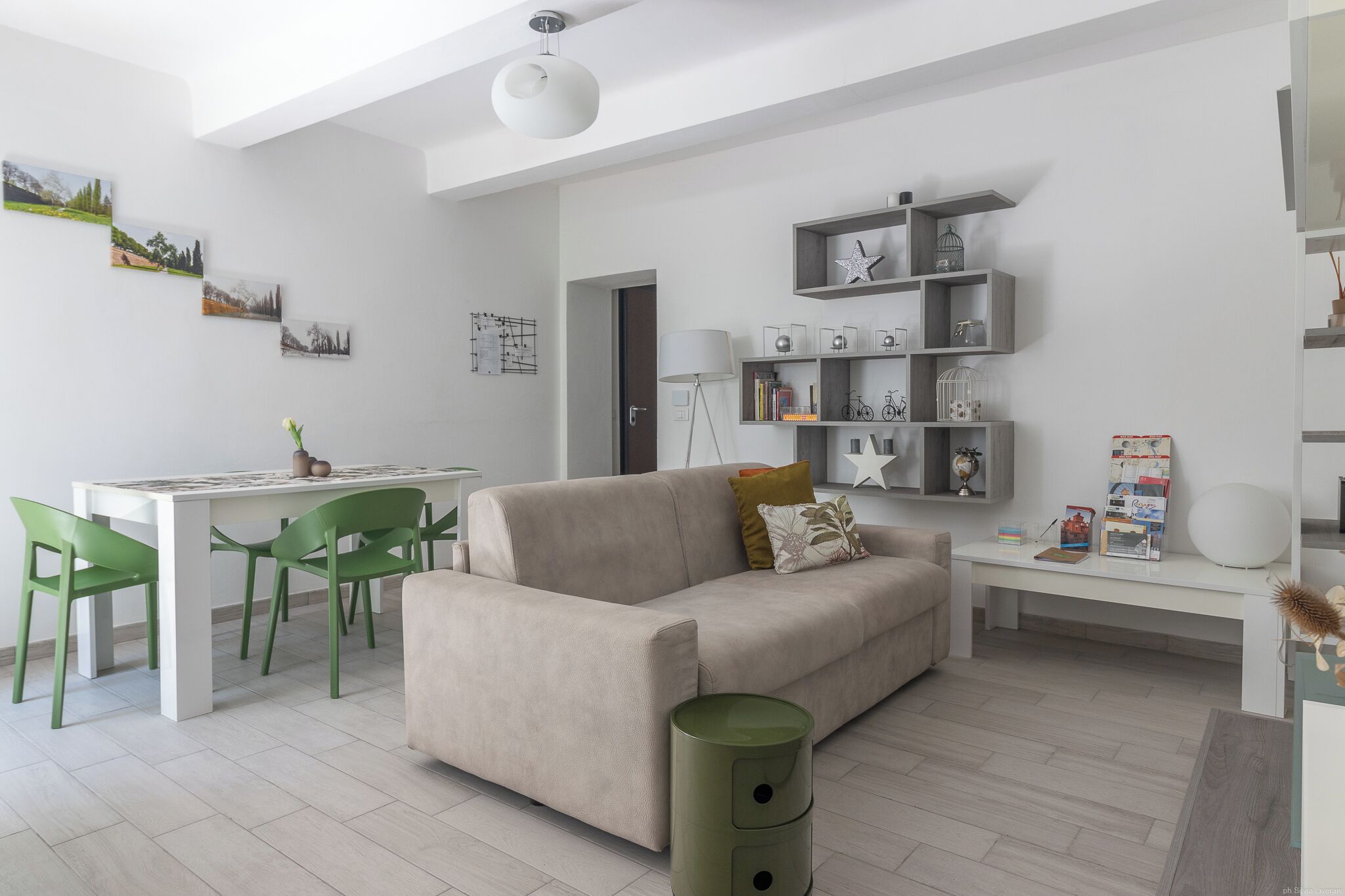 Ein modernes Wohnzimmer mit einer Couch, Esstisch, Stühlen und einem Bücherregal.