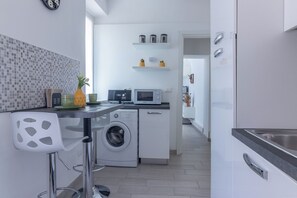 A modern kitchen with a washing machine, microwave, and a bar stool. - Apartment for two people in the city center with a garden, bicycles, and a garage (Ferrara)