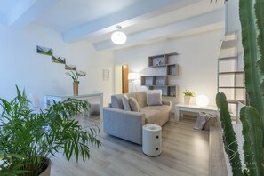 Un salon moderne avec un canapé, une table basse et une lampe. On y trouve également des plantes et un cactus.