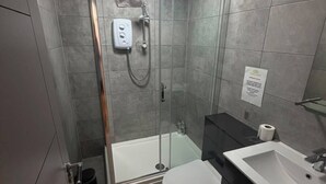 Un baño moderno con ducha de vidrio, inodoro blanco y lavamanos.