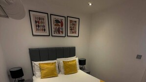 Una habitación de hotel moderna con una cama grande, dos mesitas de noche y un cabecero.