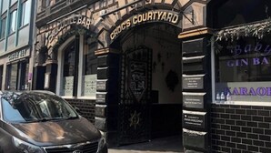 Un edificio con varias fachadas comerciales, incluyendo Croc's Courtyard y The Bar.