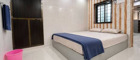 Un dormitorio moderno con una cama, un ventanal y un cubo rosa.