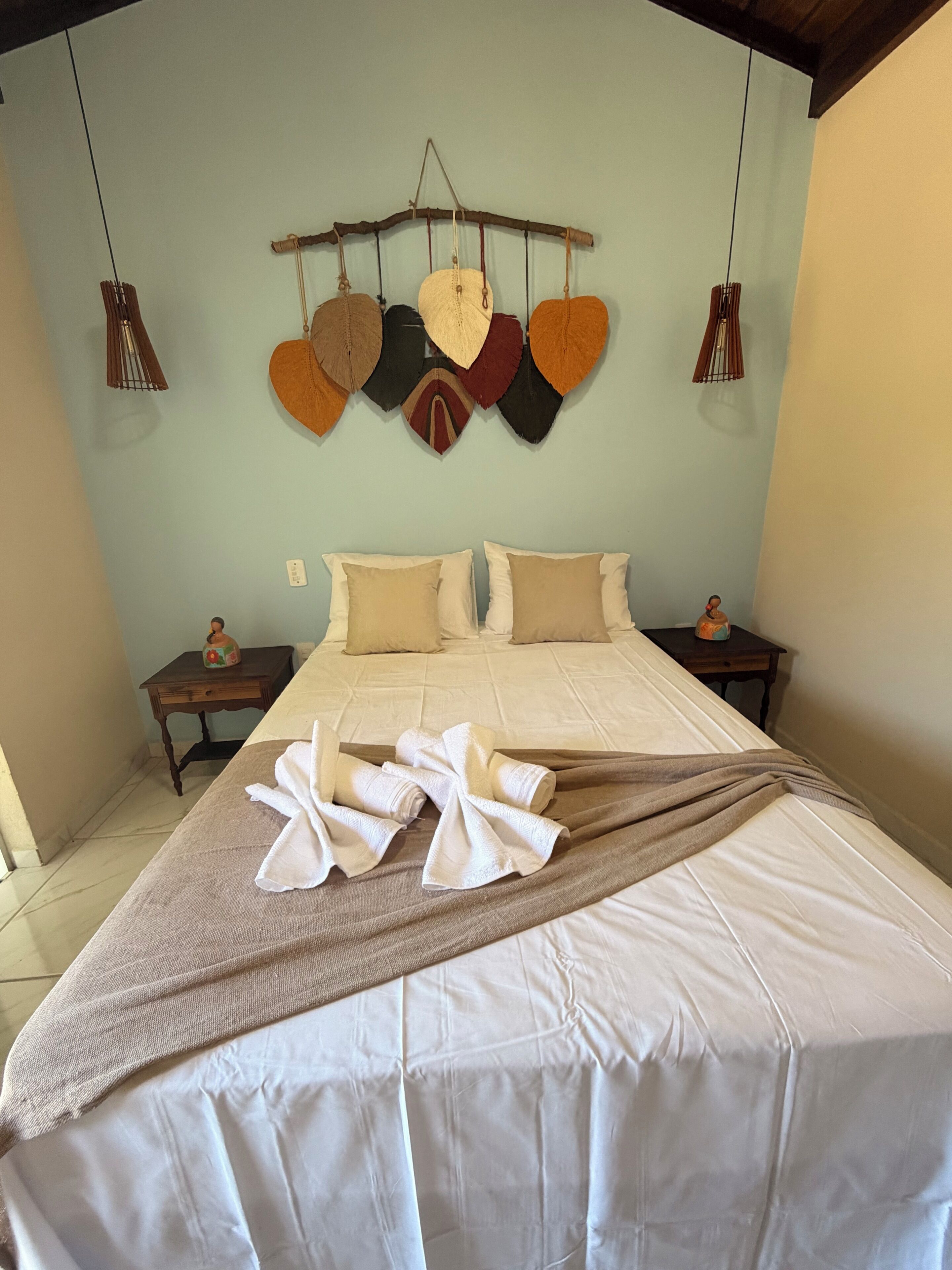 Ein Hotelzimmer mit einem Bett, zwei Nachttischen, einer an der Wand befestigten herzförmigen Dekoration und einer Pendelleuchte.
