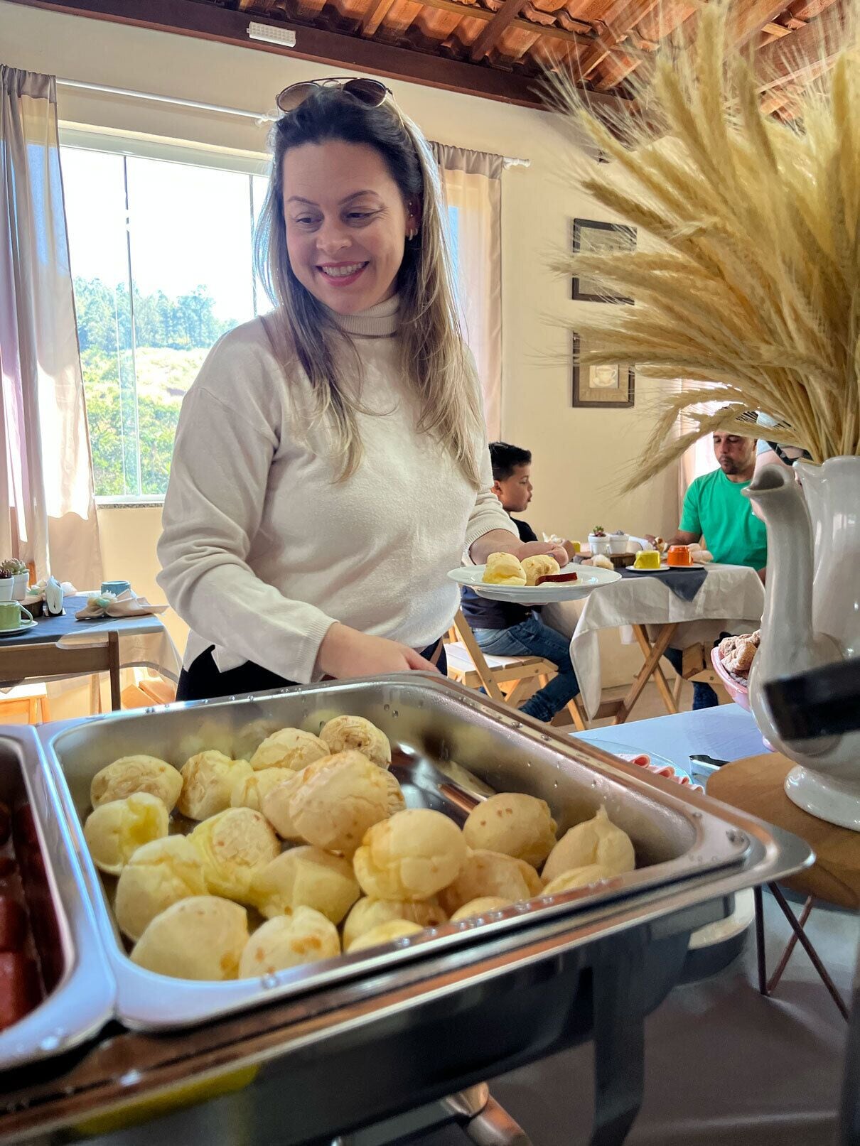 Disposição de buffet com diversos alimentos, incluindo pães e um recipiente com carne vermelha.