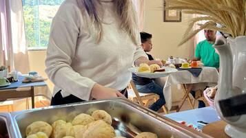 Disposição de buffet com diversos alimentos, incluindo pães e um recipiente com carne vermelha.