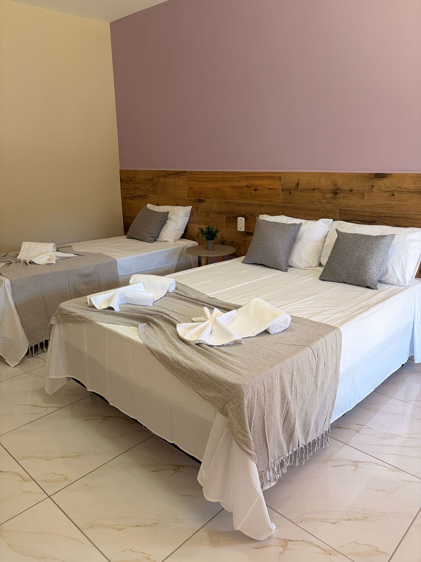 Ein Hotelzimmer mit zwei Betten, jeweils mit weißer Bettwäsche und einer grauen Decke.