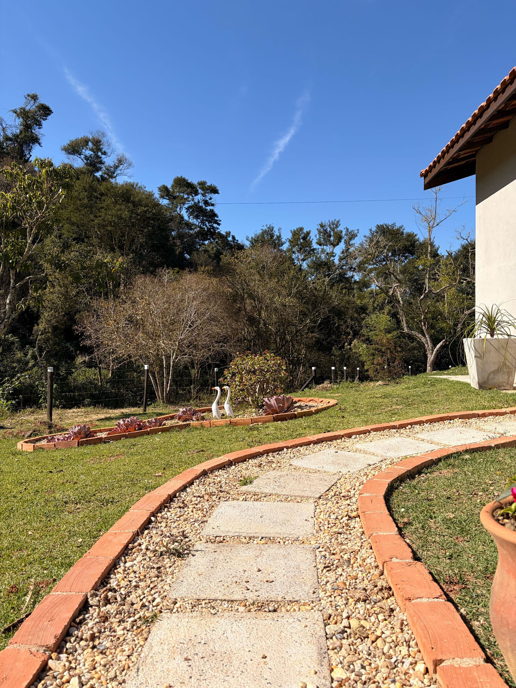Un sendero en un jardín que lleva a un edificio con techo de tejas.