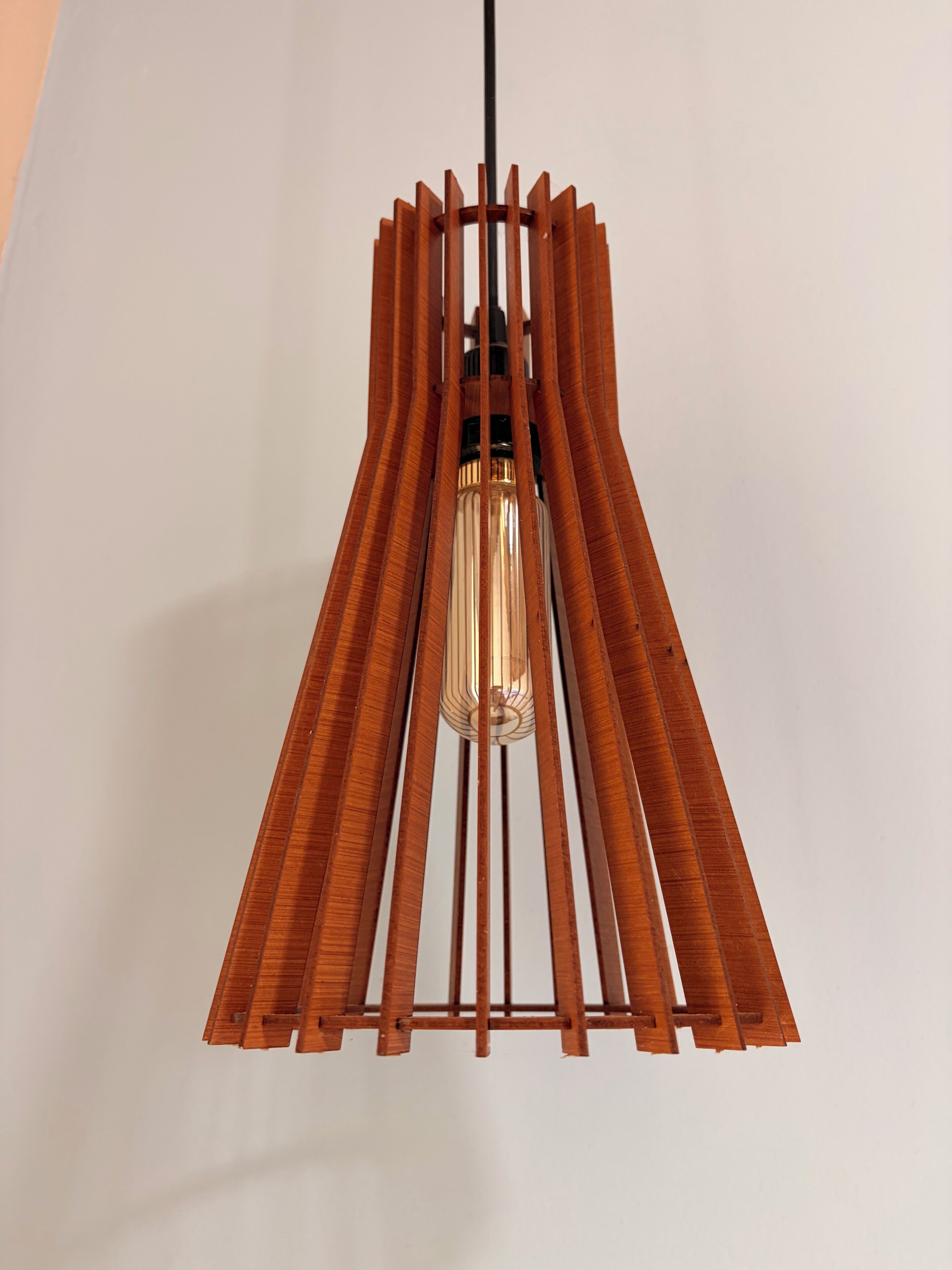 Una lámpara colgante con estructura de madera y cubierta de vidrio transparente.