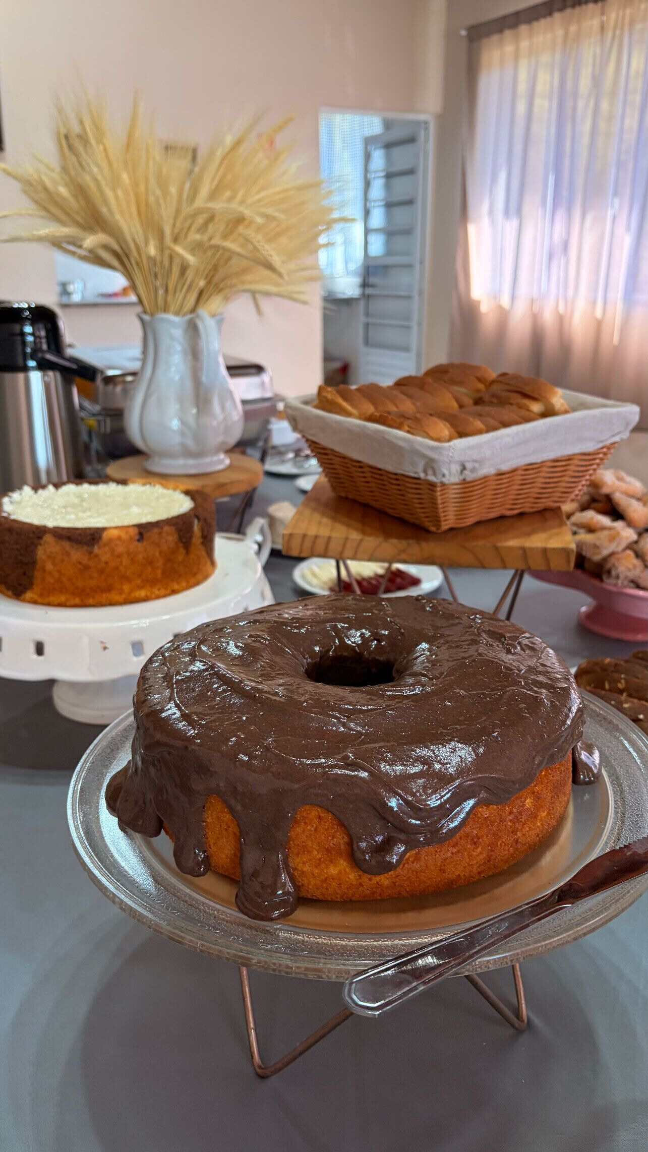 A cake with chocolate glaze on a glass stand.