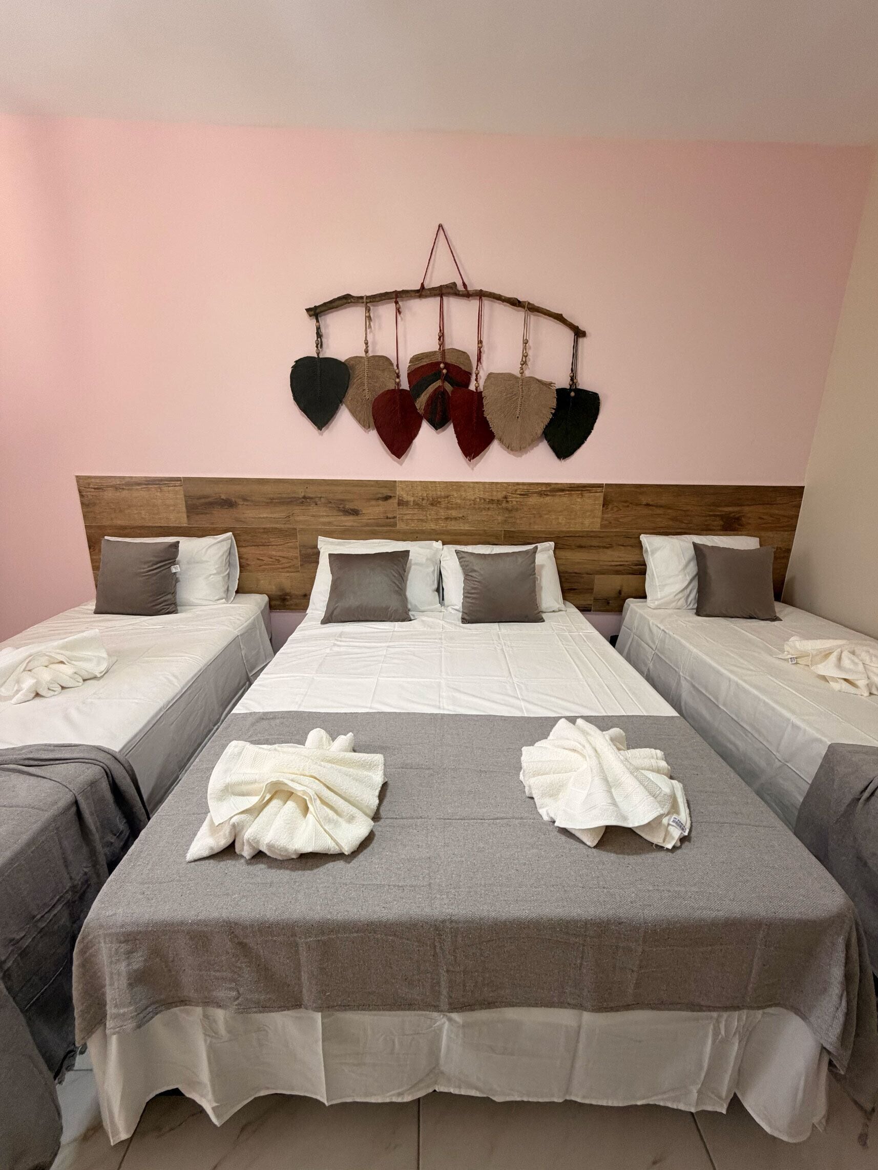 Habitació d'hotel amb un capçal de llit de fusta, un llit amb roba de llit blanca, dues taules de nit i una decoració de cor penjada a la paret.