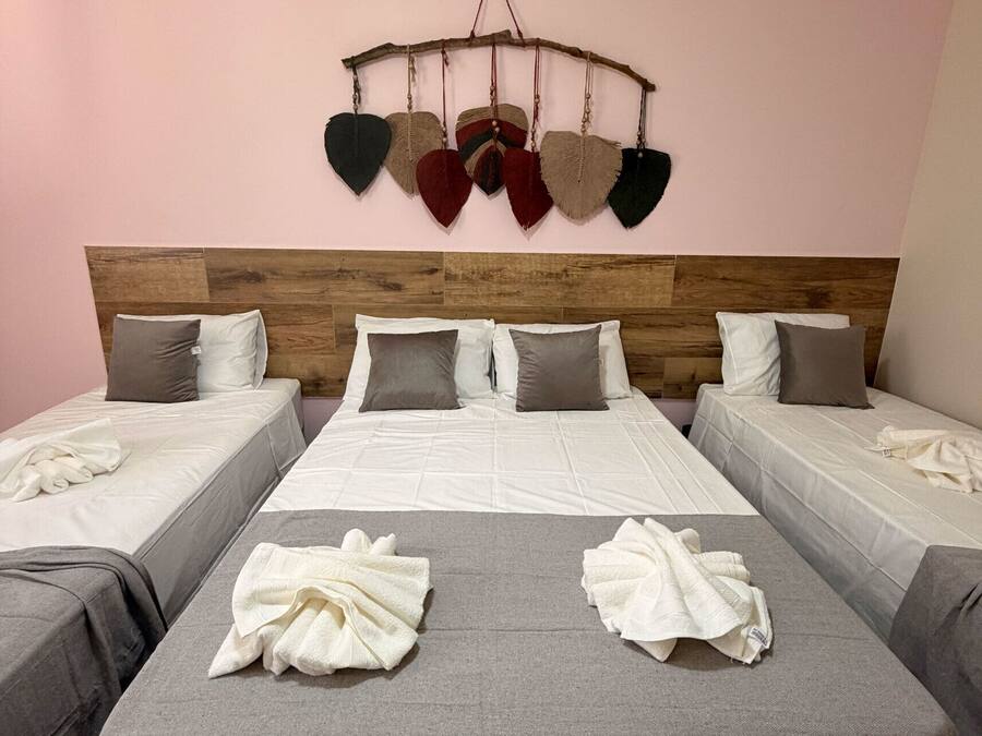 Habitació d'hotel amb un capçal de llit de fusta, un llit amb roba de llit blanca, dues taules de nit i una decoració de cor penjada a la paret.