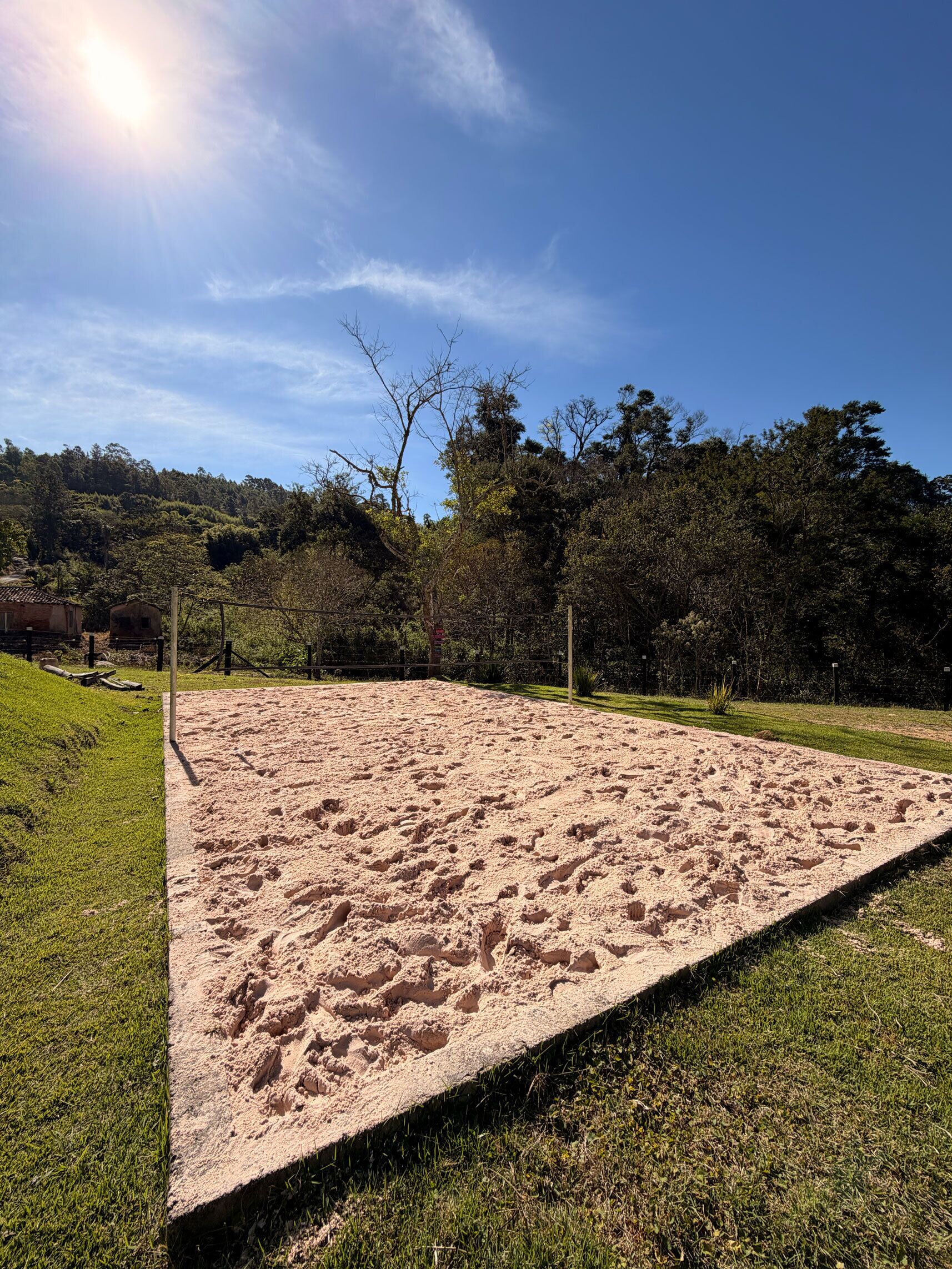 A sandy beach area with a clear sky and trees in the background.