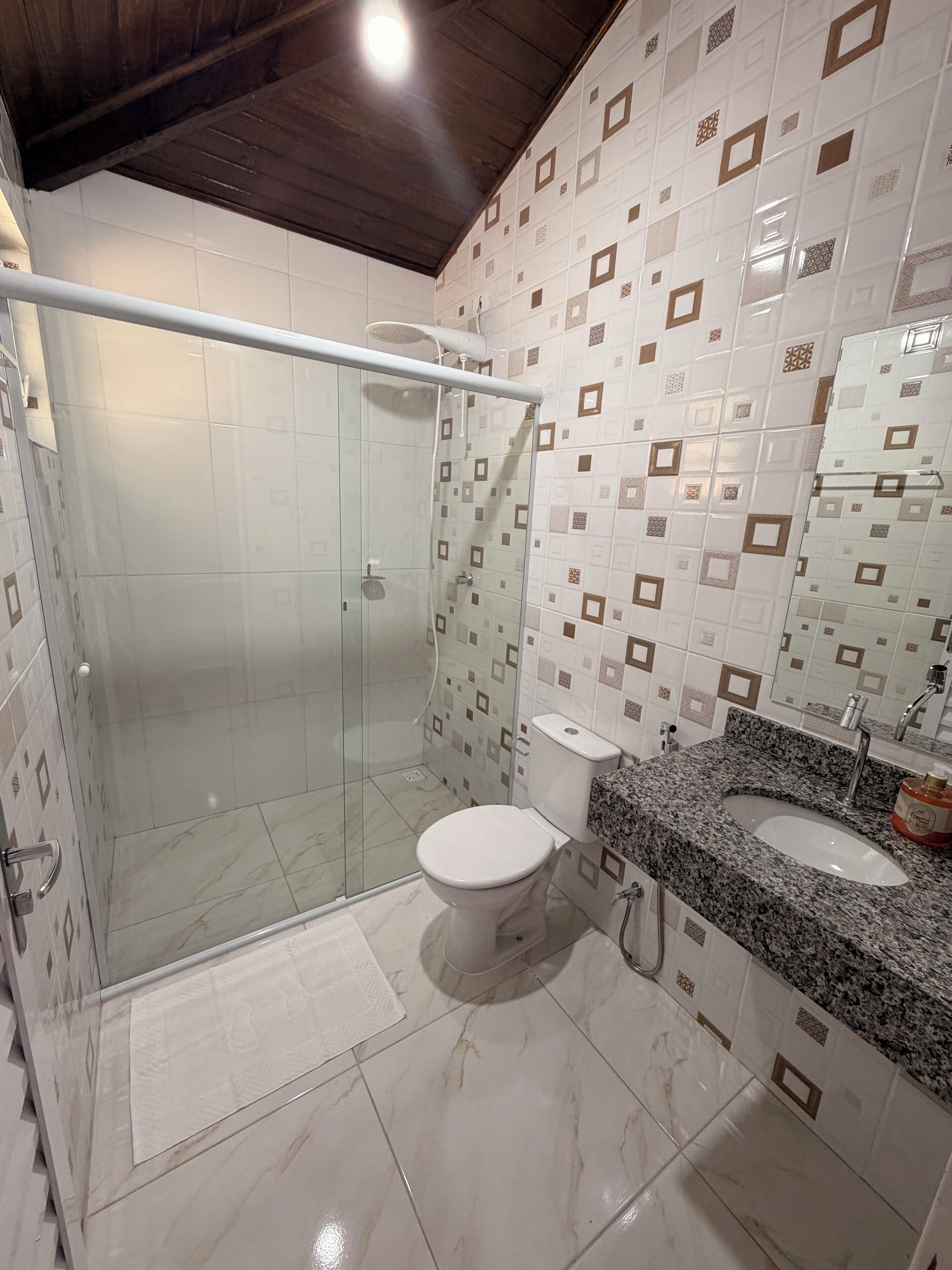 Un baño con ducha de vidrio, inodoro y lavamanos con encimera de granito.