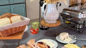 Una mesa de buffet con pan, pasteles, queso y jamón.