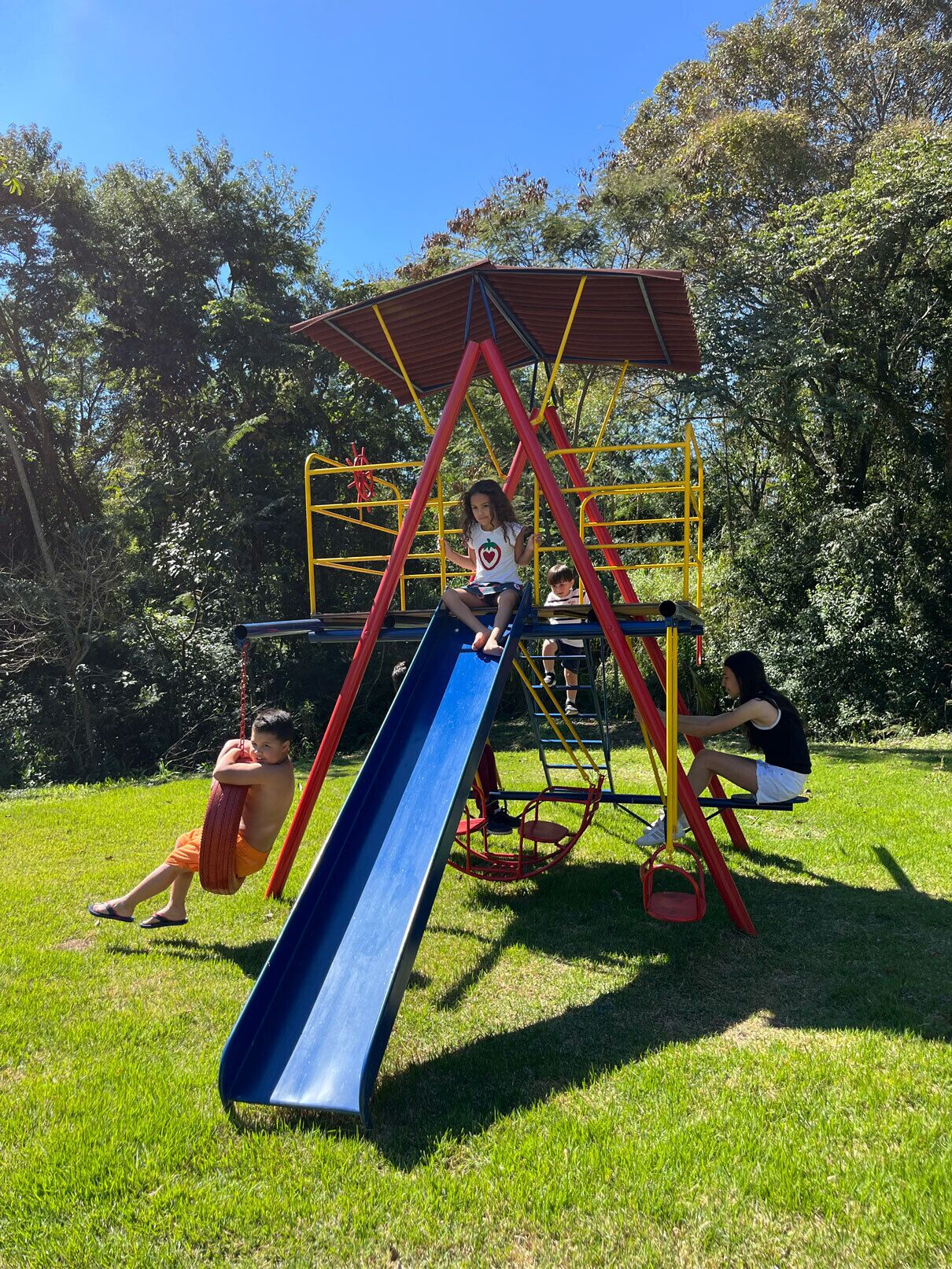 A playground with a slide, climbing structures, and a covered area.