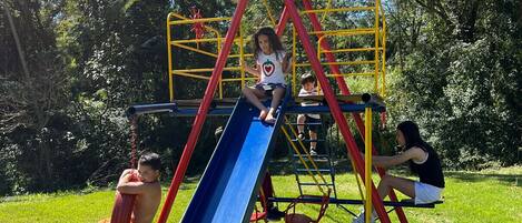 A playground with a slide, climbing structures, and a covered area.