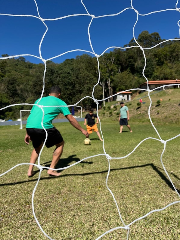A soccer game in progress on a grassy field with a net in the foreground.