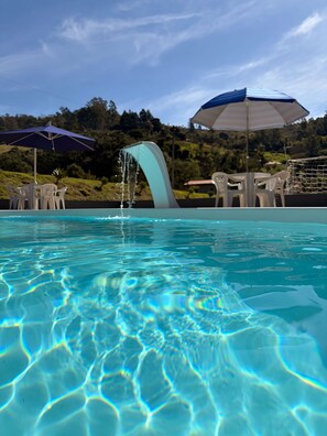 A swimming pool with clear water, surrounded by outdoor furniture and umbrellas.
