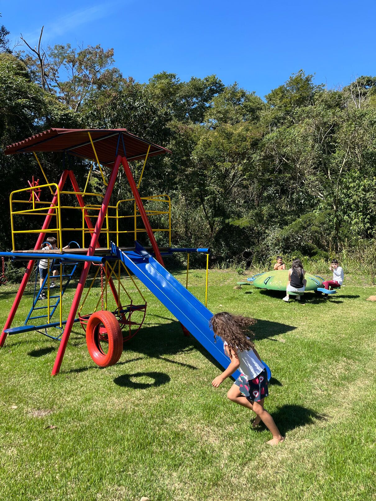 Un parque infantil con tobogán, estructuras para escalar y un columpio de neumático.