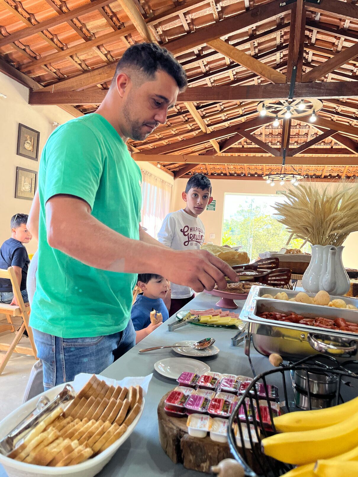 A person serving food at a buffet with various dishes and a decorative vase.