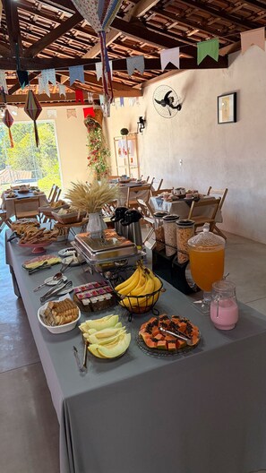 A buffet table with various food items and a pitcher of orange juice. - Pousada Vale do Arco Íris (Serra Negra)